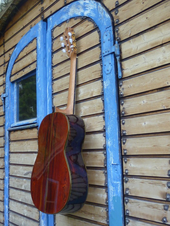 Meistergitarre Kingsize Concertguitar Modelo Orfeo (Guitarras Calliope), Fichte. Cocobolo Korpus Rückseite. Zargen. hängt an einer Zirkuswagentür. Photo © UK